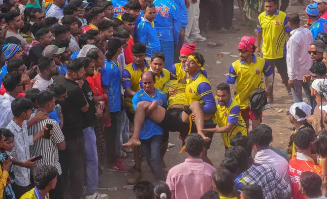Volunteers carry an injured participant who was hurt while competing in the erection of ceremonial bamboo poles, during a centuries-old annual tradition honoring goddess Raiba Devi in Rave village, near Mumbai, India, Friday, April 17, 2026. (AP Photo/Rafiq Maqbool)