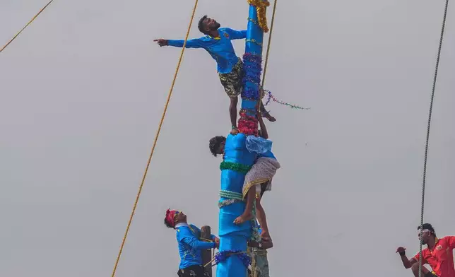 Members of the Agri-Koli community compete to erect ceremonial bamboo poles in a centuries-old annual tradition honoring the local goddess Raiba Devi, in Rave village near Mumbai, India, Friday, April 17, 2026. (AP Photo/Rafiq Maqbool)