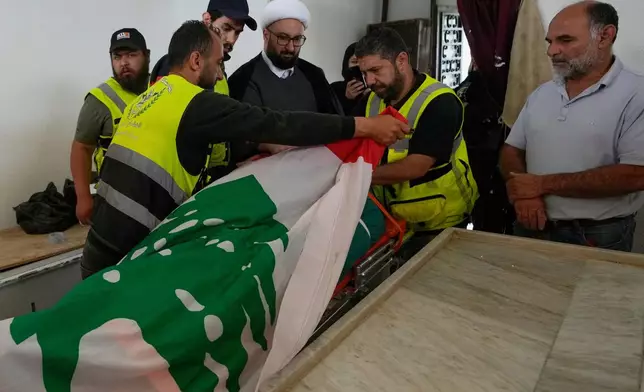 Paramedics cover the body of Ghadir Baalbaki, 19, who was killed on Tuesday in an Israeli airstrike, with a Lebanese flag at a morgue in the southern port city of Tyre, Lebanon, Wednesday, April 15, 2026. (AP Photo/Hussein Malla)