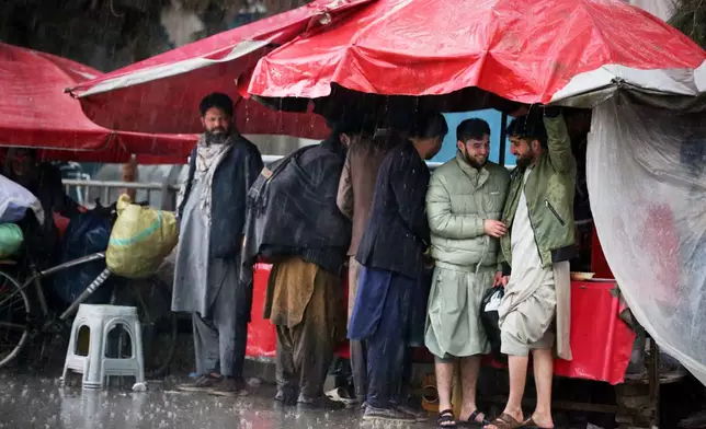 Residents take cover from heavy rain at a market in Kabul, Afghanistan, Tuesday, March 31, 2026. (AP Photo/Siddiqullah Alizai)