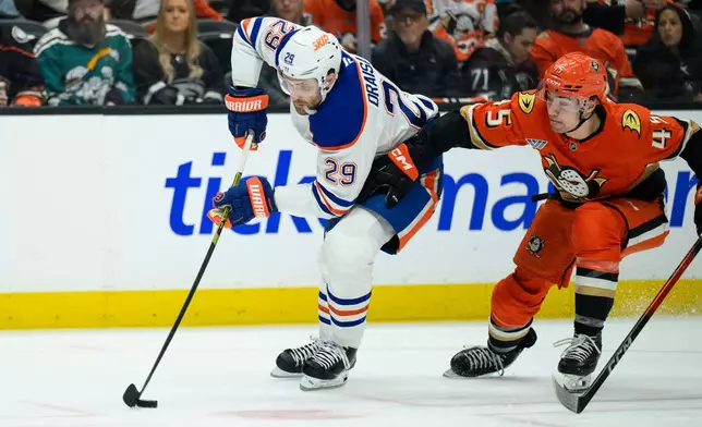 Edmonton Oilers center Leon Draisaitl, left, controls the puck as Anaheim Ducks right wing Beckett Sennecke defends during the second period of Game 4 in the first round of an NHL hockey Stanley Cup playoff series Sunday, April 26, 2026, in Anaheim, Calif. (AP Photo/Kyusung Gong)