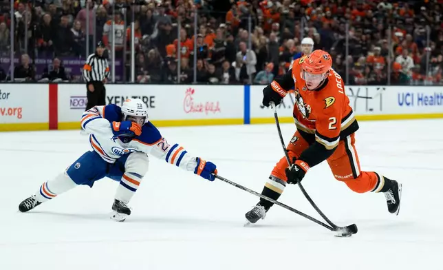 Edmonton Oilers center Matt Savoie, left, blocks the shot by Anaheim Ducks defenseman Jackson LaCombe during the third period of Game 4 in the first round of an NHL hockey Stanley Cup playoff series Sunday, April 26, 2026, in Anaheim, Calif. (AP Photo/Kyusung Gong)