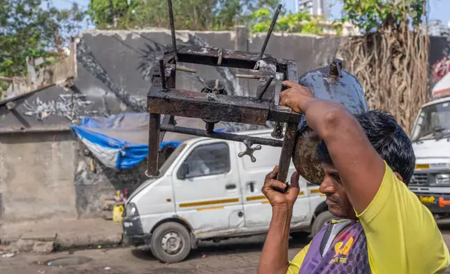 A fisherman carries a stove as he walks towards his boat at Sassoon Dock In Mumbai, India, Wednesday, April 8, 2026. (AP Photo/Rafiq Maqbool)
