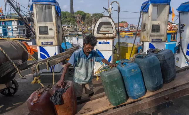 A deckhand arranges empty fuel cans on his handcart at Sassoon Dock beside a cooperative diesel pump that is shut due to rising bulk fuel prices in Mumbai, India, Tuesday, April 7, 2026. (AP Photo/Rafiq Maqbool)