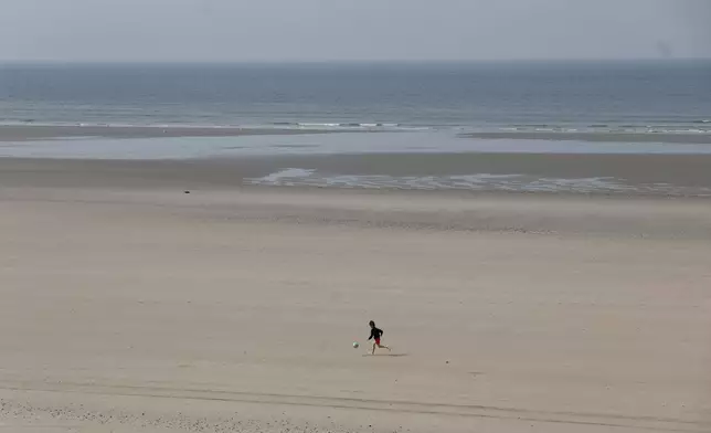 A young boy runs on the beach after at least four people died while trying to board an inflatable boat for a dangerous sea crossing from northern France to the U.K. in Equihen-Plage, northern France. Thursday, April 9, 2026. (AP Photo/Jean-Francois Badias)