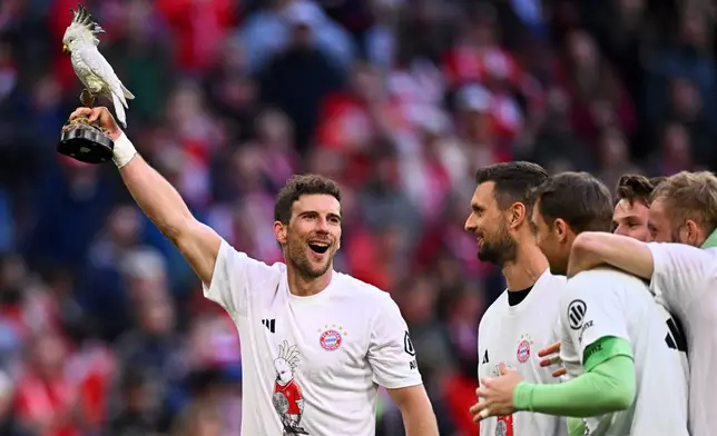 Bayern's Leon Goretzka, holds a cockatoo trophy as he celebrates after winning the German championship at the end of the Bundesliga soccer match between Bayern and Stuttgart in Munich, Germany, Sunday, April 19, 2026. (Tom Weller/dpa via AP)