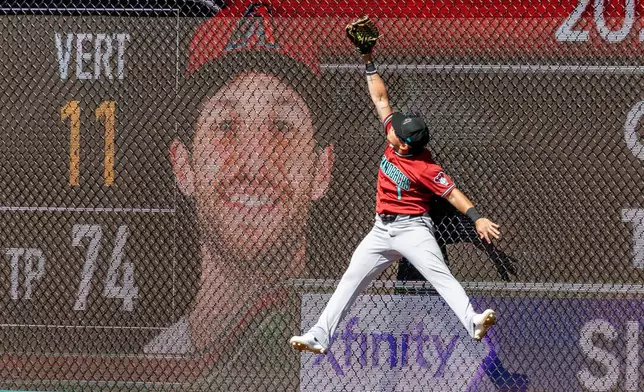 Arizona Diamondbacks left fielder Jorge Barrosa reaches for a home run hit by Philadelphia Phillies' Trea Turner during the sixth inning of a baseball game, Sunday, April 12, 2026, in Philadelphia. (AP Photo/Laurence Kesterson)