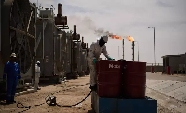 A worker collects engine oil as he works at a degassing station in Zubair oil field, whose operations have being reduced due to the Mideast war triggered by the U.S. and Israeli attacks on Iran, near Basra, Iraq, Saturday, March 28, 2026. (AP Photo/Leo Correa)