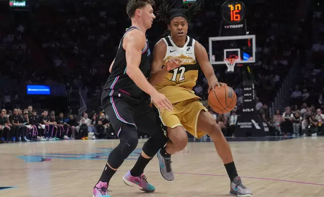 Miami Heat guard Pelle Larsson (9) defends Washington Wizards guard Tre Johnson (12) during the first half of an NBA basketball game Saturday, April 4, 2026, in Miami. (AP Photo/Marta Lavandier)