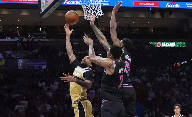Washington Wizards forward Justin Champagnie (9) aims to score as Miami Heat forward Andrew Wiggins (22) and center Kel'el Ware (7) defend during the first half of an NBA basketball game Saturday, April 4, 2026, in Miami. (AP Photo/Marta Lavandier)