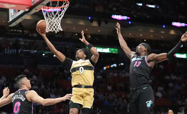 Washington Wizards guard Bilal Coulibaly (0) aims to score as Miami Heat forward Simone Fontecchio (0) and center Bam Adebayo (13) defend during the first half of an NBA basketball game Saturday, April 4, 2026, in Miami. (AP Photo/Marta Lavandier)