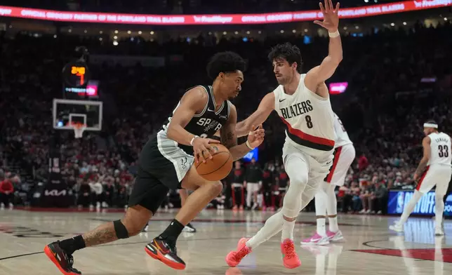 San Antonio Spurs guard Dylan Harper (2) drives against Portland Trail Blazers forward Deni Avdija (8) during the second half in Game 3 of a first-round NBA playoffs basketball series in Portland, Ore, Friday, April 24, 2026. (AP Photo/Jenny Kane)