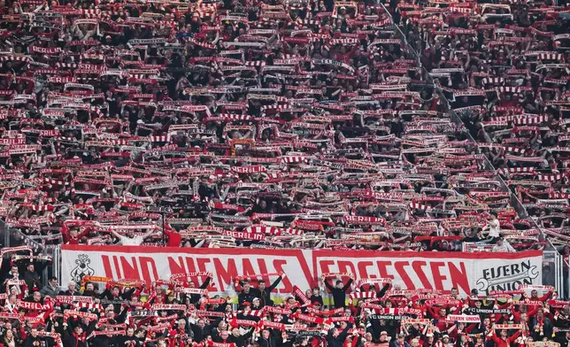 Union Berlin supporters hold up scarves and cheer during a Bundesliga soccer match between RB Leipzig and 1. FC Union Berlin, Friday, April 24, 2026, in Leipzig, Germany. (Jan Woitas/dpa via AP)