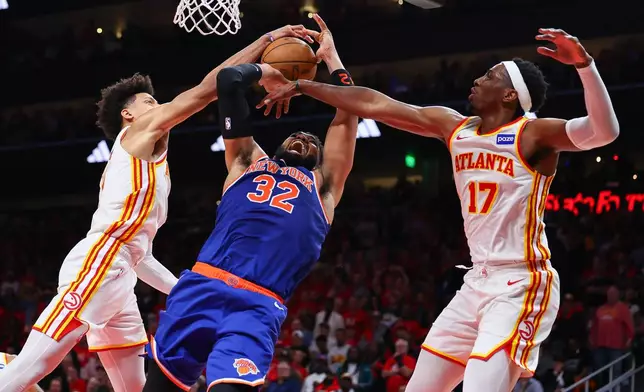 Atlanta Hawks forward Jalen Johnson, left, blocks a shot from New York Knicks center Karl-Anthony Towns (32) while forward Onyeka Okongwu (17) defends during the second half in Game 3 of a first-round NBA playoffs basketball series, Thursday, April 23, 2026, in Atlanta. (AP Photo/Colin Hubbard)