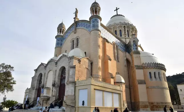 People sit outside the Church of Notre Dame d'Afrique, ahead of Pope Leo XIV's visit, in Algiers, Algeria, Wednesday, April 8, 2026. (AP Photo/Fateh Guidoum)
