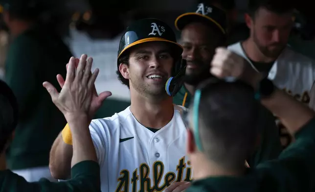 Athletics' Max Muncy, center, celebrates after scoring during the first inning of a home-opener baseball game against the Houston Astros, Friday, April 3, 2026, in West Sacramento, Calif. (AP Photo/Sara Nevis)