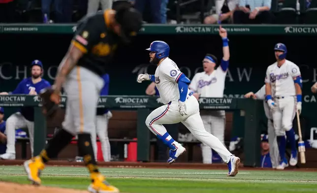 Texas Rangers' Jake Burger, center, sprints to first with a two-run single as Pittsburgh Pirates pitcher Gregory Soto, front left, reacts to the play in the eighth inning of a baseball game Wednesday, April 22, 2026, in Arlington, Texas. (AP Photo/Tony Gutierrez)