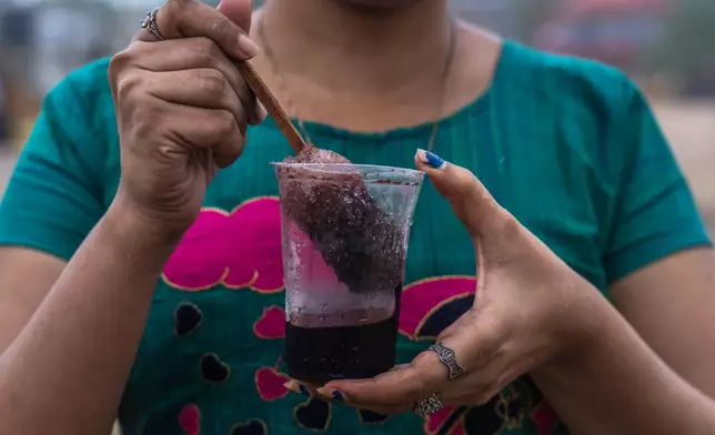 FILE - A girl hold a plastic glass as she prepares to drink Shaved ice at Juhu beach in Mumbai, India, on June 30, 2022. (AP Photo/Rafiq Maqbool, File)
