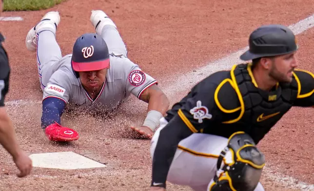 Washington Nationals' Jorbit Vivas, left, slides into home as Pittsburgh Pirates catcher Joey Bart, right, waits for a late relay throw on a single by Nationals' James Wood off Pirates pitcher Dennis Santana during the 10th inning of a baseball game in Pittsburgh, Thursday, April 16, 2026. (AP Photo/Gene J. Puskar)