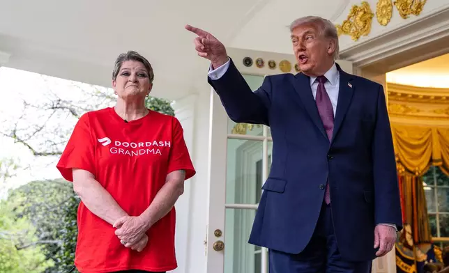 Sharon Simmons with DoorDash, listens as President Donald Trump speaks with reporters outside the Oval Office of the White House, Monday, April 13, 2026, in Washington. (AP Photo/Alex Brandon)