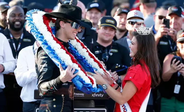 Carson Hocevar is presented a wreath from Miss Alabama Hailey Adams after winning a NASCAR Cup Series auto race, Sunday, April 26, 2026, in Talladega, Ala. (AP Photo/Butch Dill)