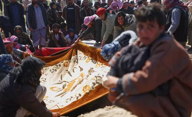 Mourners cover a grave with cloth during the burial of a woman from the Al-Jalib family, among six relatives killed Wednesday in Israeli strikes in Beirut, during their funeral in the village of al-Sour, Deir al-Zour province, northeastern Syria, Saturday, April 11, 2026. The cloth is held to preserve privacy and shield the body from view.(AP Photo/Ghaith Alsayed)