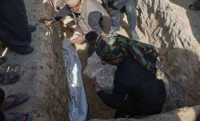 One of six members of the Al-Jalib family killed Wednesday in Israeli strikes in Beirut is covered after being placed in the grave during their funeral in the village of al-Sour, Deir al-Zour province, northeastern Syria, Saturday, April 11, 2026. (AP Photo/Ghaith Alsayed)