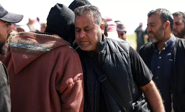 Hamad al-Jalib is comforted by mourners during the funeral of his wife and four of his five children, who were killed in Israeli strikes in Beirut earlier this week, during their funeral in the village of al-Sour, Deir al-Zour province, northeastern Syria, Saturday, April 11, 2026. (AP Photo/Ghaith Alsayed)