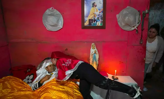 A pilgrim kisses her sick grandfather, Ramon Gamboa, after a priest blessed him at his home during the Quasimodo Feast, a procession held the Sunday following Easter, Colina, Chile, Sunday, April 12, 2026. (AP Photo/Esteban Felix)
