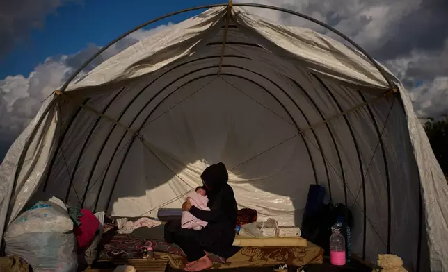 Haifa Kenjo, who fled Israeli airstrikes on the southern suburbs of Beirut, holds her 15-day-old daughter Shiman inside the tent she uses as a shelter and where she gave birth to her in Beirut, Sunday, April 12, 2026. (AP Photo/Emilio Morenatti)