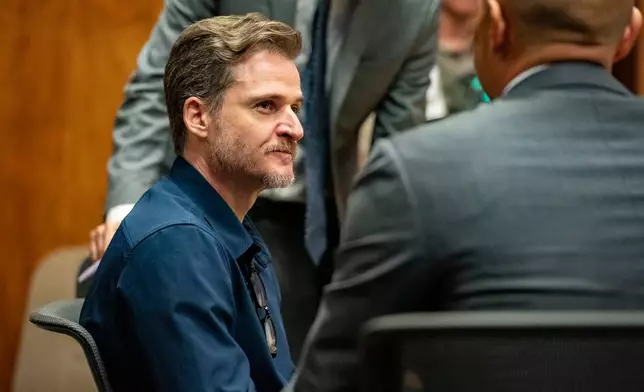 Gerhardt Konig, left, talks to his defense lawyer Thomas Otake after closing arguments in his attempted murder trial in a courtroom, Tuesday, April 7, 2026, in Honolulu. (AP Photo/Mengshin Lin, Pool)
