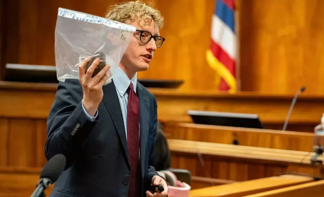 Deputy Prosecutor Joel Garner holds a rock as evidence while presenting closing arguments during the attempted murder trial of Gerhardt Konig in a courtroom, Tuesday, April 7, 2026, in Honolulu. (AP Photo/Mengshin Lin, Pool)