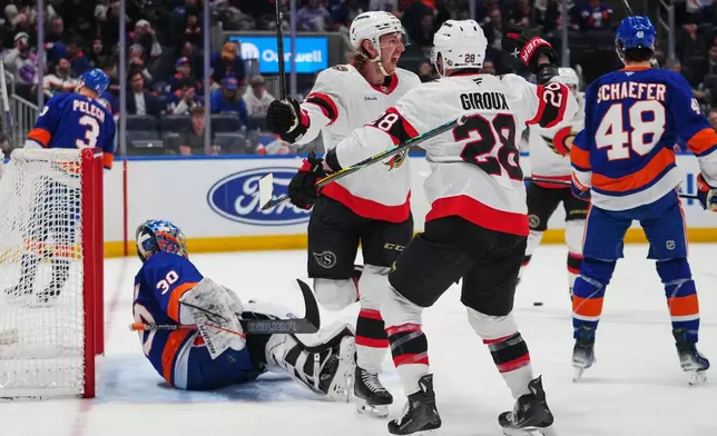 Ottawa Senators' Jake Sanderson (85) celebrates with Claude Giroux (28) after scoring a goal as New York Islanders goaltender Ilya Sorokin (30) watches during the third period of an NHL hockey game Saturday, April 11, 2026, in Elmont, N.Y. (AP Photo/Frank Franklin II)
