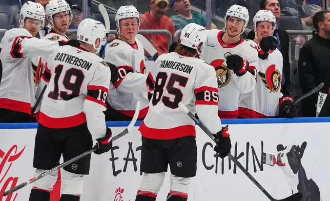 Ottawa Senators' Jake Sanderson (85) and Drake Batherson (19) celebrate with teammates after Sanderson scored a goal during the third period of an NHL hockey game against the New York Islanders Saturday, April 11, 2026, in Elmont, N.Y. (AP Photo/Frank Franklin II)