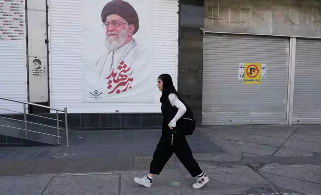 A woman walks past a poster of the late Iranian Supreme Leader Ayatollah Ali Khamenei in downtown Tehran, Iran, Sunday, April 5, 2026. (AP Photo/Vahid Salemi)