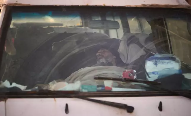 A man, who fled Israeli bombings in southern Lebanon with his family, sleeps in his car used as shelter, along a seaside promenade in downtown Beirut, Lebanon, Sunday, April 5, 2026. (AP Photo/Emilio Morenatti)