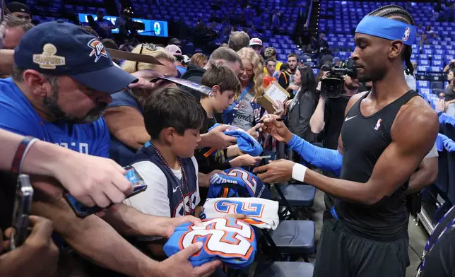 FILE - Oklahoma City Thunder guard Shai Gilgeous-Alexander, right, gives autographs to fans before Game 1 of a first-round NBA playoffs basketball series against the Phoenix Suns, Sunday, April 19, 2026, in Oklahoma City. (AP Photo/Nate Billings, File)