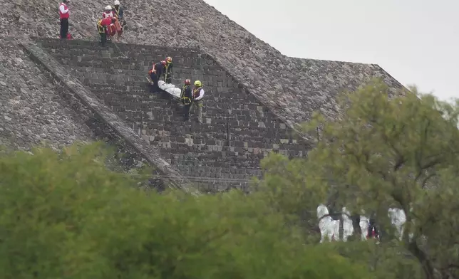 Forensic workers carry the body of a victim down a pyramid after authorities said a gunman opened fire, in Teotihuacan, Mexico, Monday, April 20, 2026. (AP Photo/Eduardo Verdugo)