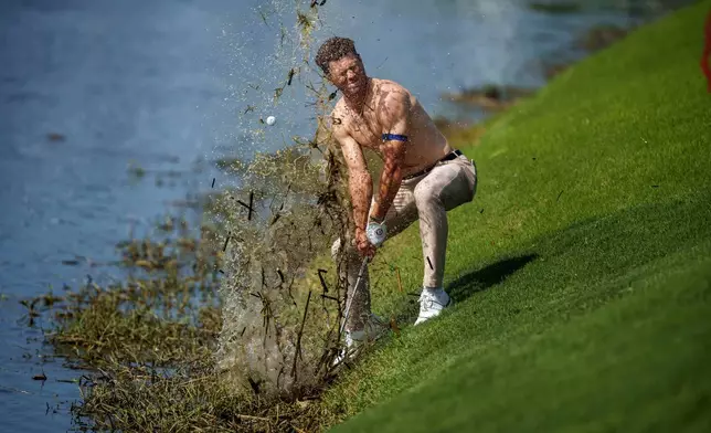 Michael Brennan sends mud and water flying as he tries to hit his ball out of floating debris on the 18th hole, only to have it land back in the water, during the first round of the PGA Zurich Classic golf tournament at TPC Louisiana, Thursday, April 23, 2026, in Avondale, La. (AP Photo/Matthew Hinton)