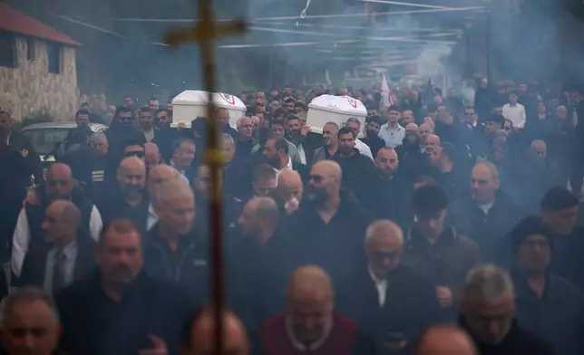 Men carry the coffins with the bodies of Pierre Mouawad, an official with the anti-Hezbollah Lebanese Forces party, and his wife during their funeral in Yahshush, in Lebanon, Tuesday, April 7, 2026. (AP Photo/Emilio Morenatti)