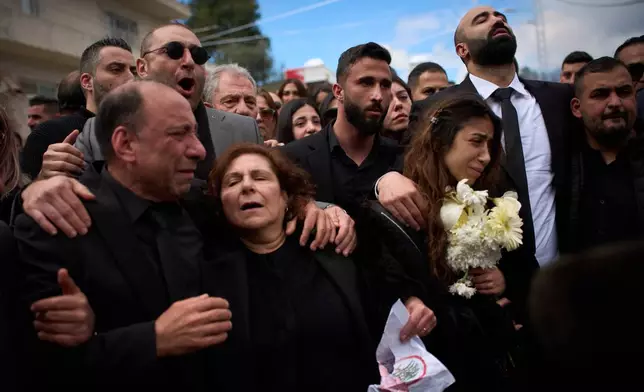 Gyal, right, daughter of Pierre Mouawad, an official with the anti-Hezbollah Lebanese Forces party, and his wife, walks as men carry the bodies of her parents during their funeral in Yahshush, Lebanon, Tuesday, April 7, 2026. (AP Photo/Emilio Morenatti)