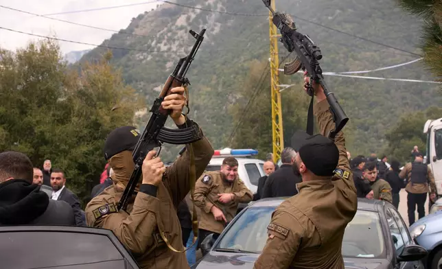 Gunmen fire their weapons as men carry the coffins with the bodies of Pierre Mouawad, an official with the anti-Hezbollah Lebanese Forces party, and his wife during their funeral in Yahshush, in Lebanon, Tuesday, April 7, 2026. (AP Photo/Emilio Morenatti)