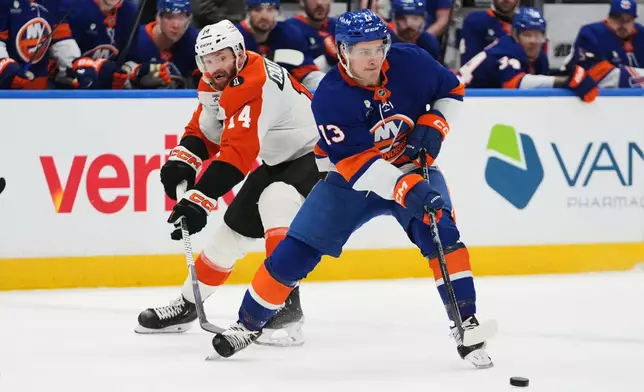Philadelphia Flyers' Sean Couturier (14) defends New York Islanders' Mathew Barzal (13) during the second period of an NHL hockey game Friday, April 3, 2026, in Elmont, N.Y. (AP Photo/Frank Franklin II)