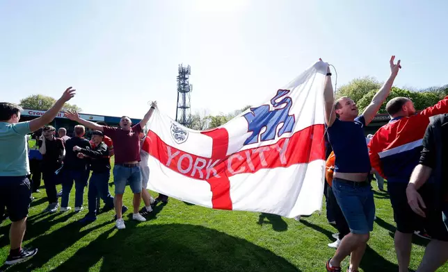 York City fans celebrate on the pitch at the final whistle after the National League match between Rochdale and York City in Rochdale, England, Saturday April 25, 2026. (Cody Froggatt/PA via AP)