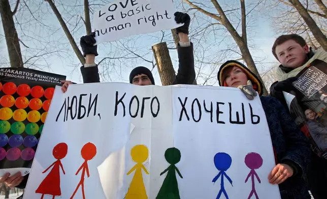 FILE - Activists hold placards during a picket, authorised by the authorities, against homophobia in front of the Department of Justice in Minsk, Belarus, Monday, Feb. 14, 2010. The sign on placard reads "Love who you want". (AP Photo, File)