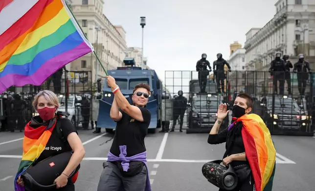FILE - LGBT activists perform with rainbow flags and an old Belarusian national flag, in front of a police barricade blocking a street during an opposition rally to protest the official presidential election results in Minsk, Belarus, Sunday, Sept. 6, 2020. (AP Photo, File)