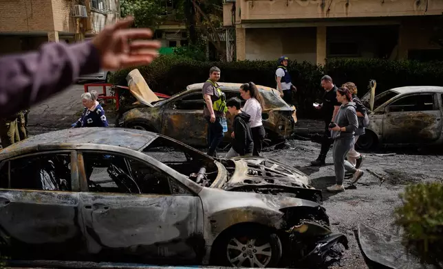 Residents and Israeli security forces inspect a site struck by an Iranian missile in Petah Tikva, Israel, Tuesday, March 31, 2026. (AP Photo/Ohad Zwigenberg)