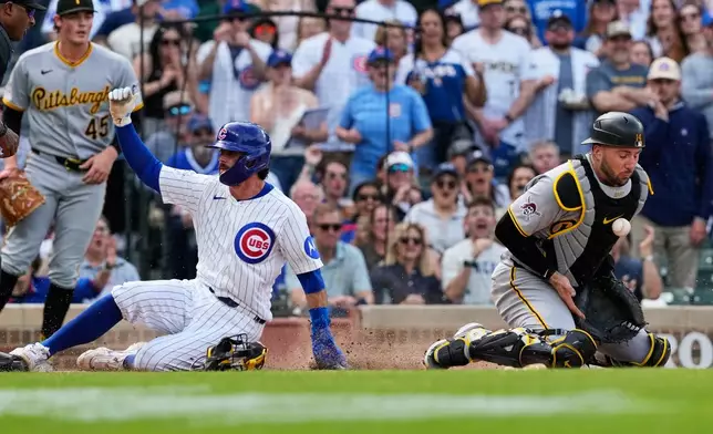 Chicago Cubs' Dansby Swanson, left, scores past Pittsburgh Pirates catcher Joey Bart during the seventh inning of a baseball game, in Chicago, Sunday, April 12, 2026. (AP Photo/Nam Y. Huh)