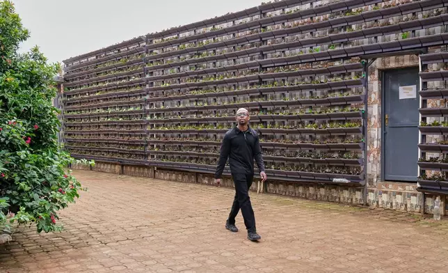 Christian Irakoze, co-founder of Eza Neza, or "Grow Well," a local company that sets up vertical farms in the city and describes them as scalable, walks inside a home compound in Kigali, Rwanda, March 18, 2026. (AP Photo/Brian Inganga)