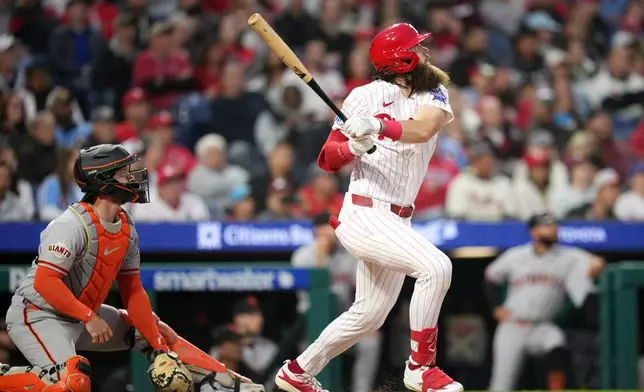 Philadelphia Phillies' Brandon Marsh, right, follows through after hitting an RBI-sacrifice fly against San Francisco Giants pitcher Tyler Mahle during the fourth inning of a baseball game Tuesday, April 28, 2026, in Philadelphia. (AP Photo/Matt Slocum)